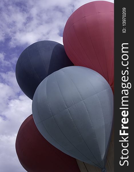 Red and blue hot air balloons attached together to one bucket before taking off