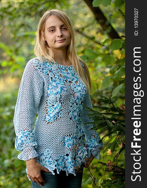 Sunburned girl in blue pullover in the forest