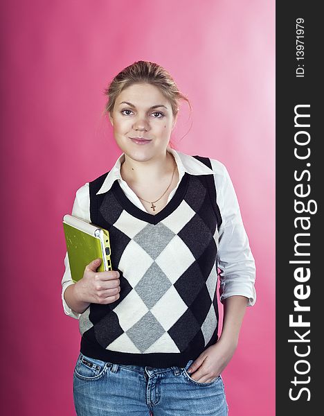 Blond young woman with green laptop posing on pink background, studio shot