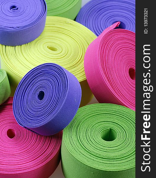 Group of multicolor elastic's bobbins. Bright vertical background with yellow,green, pink and purple spools. Group of multicolor elastic's bobbins. Bright vertical background with yellow,green, pink and purple spools.