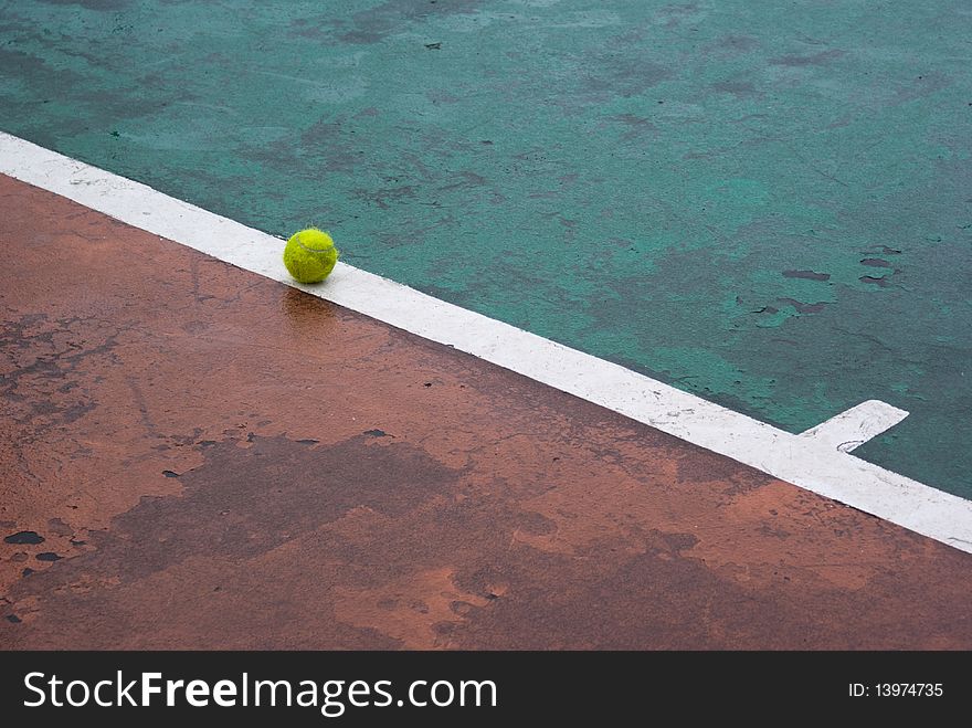 Wet tennis ball on a white line of a wet tennis court. Wet tennis ball on a white line of a wet tennis court