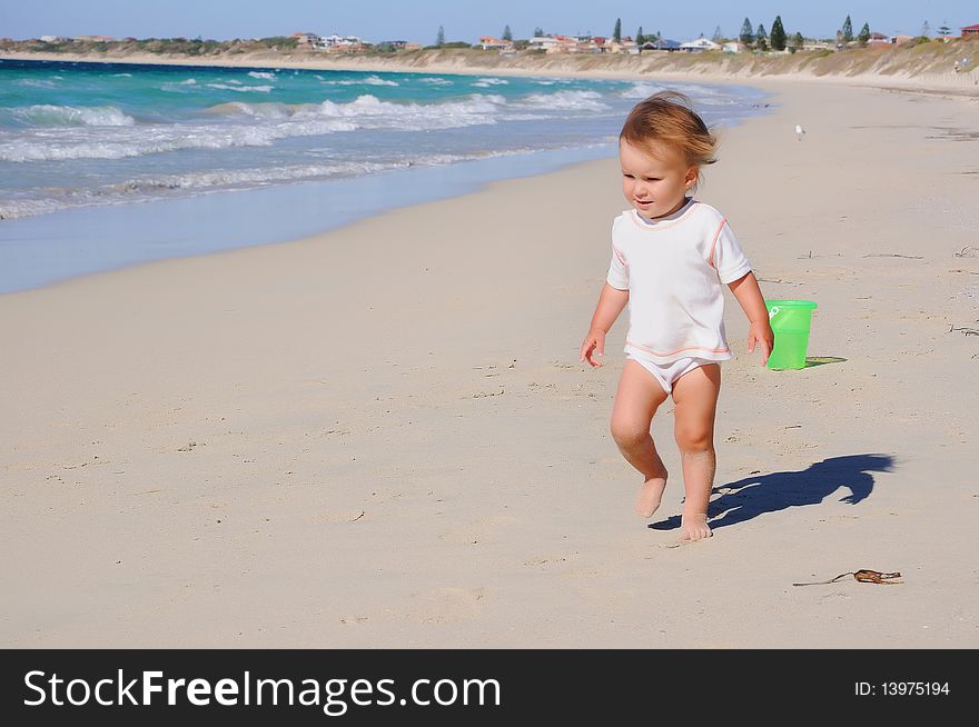 Charming little girl running on the golden beaches near the ocean blue