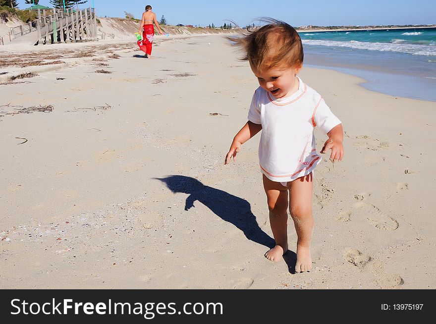 Charming little girl running on the golden beaches near the ocean blue