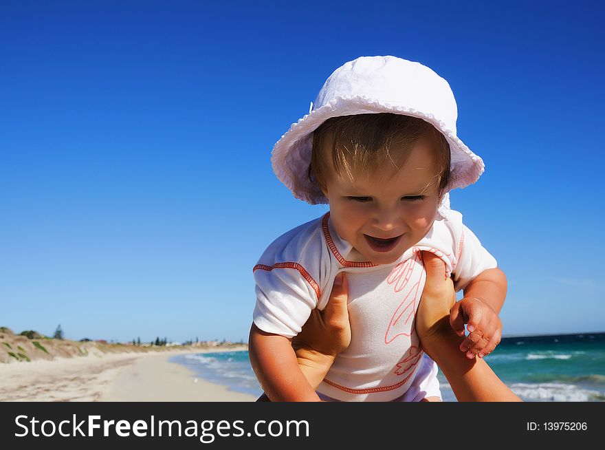 Charming little happy girl laughing in the arms of his mother, against the blue sky