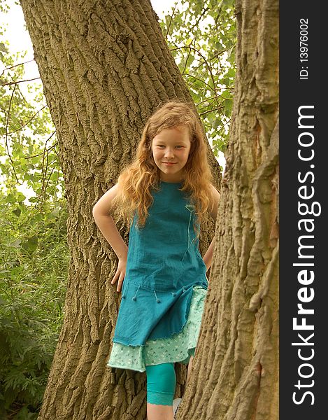 Portrait of young girl with red hair playing around trees