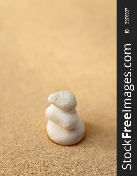 Three small white stones on a sand, vertical photo, shallow depth of view. Three small white stones on a sand, vertical photo, shallow depth of view