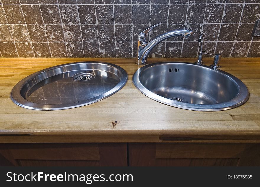 Double stainless steel kitchen sink on hard wood worktop. Double stainless steel kitchen sink on hard wood worktop