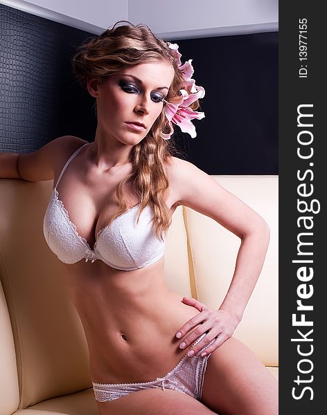 Blonde in lingerie sitting posing in sofa with madonna lily