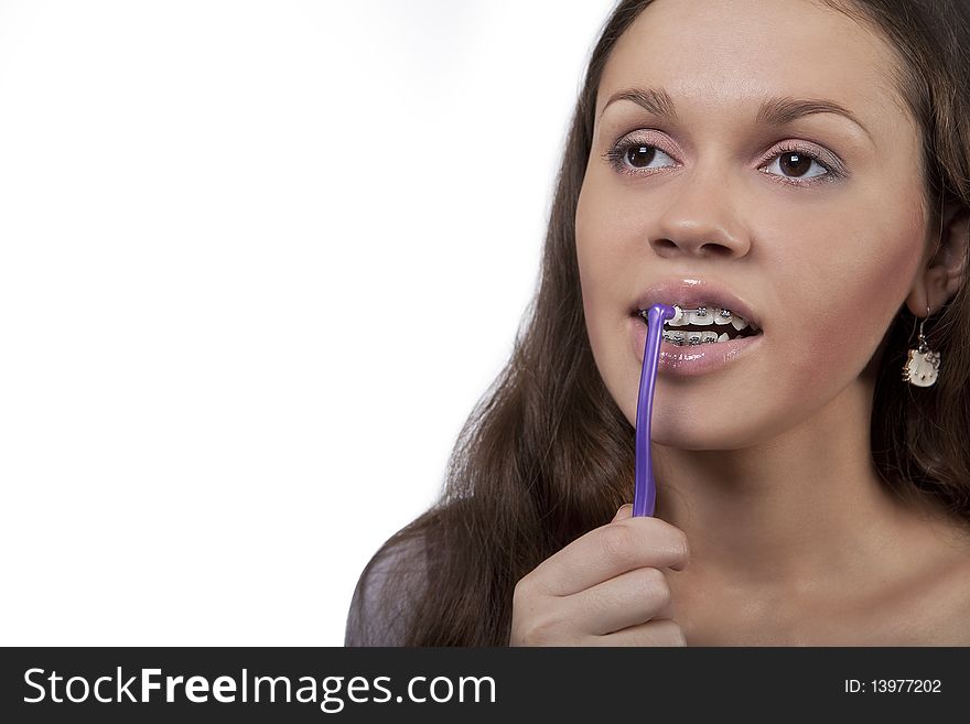 Girl with round toothbrush cleaning brackets with mouth open and eyes lifted up isolated over white background. Girl with round toothbrush cleaning brackets with mouth open and eyes lifted up isolated over white background