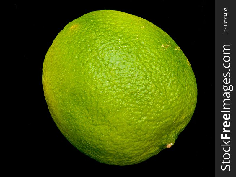 A macro image of a single lime isolated on a dark background. A macro image of a single lime isolated on a dark background.