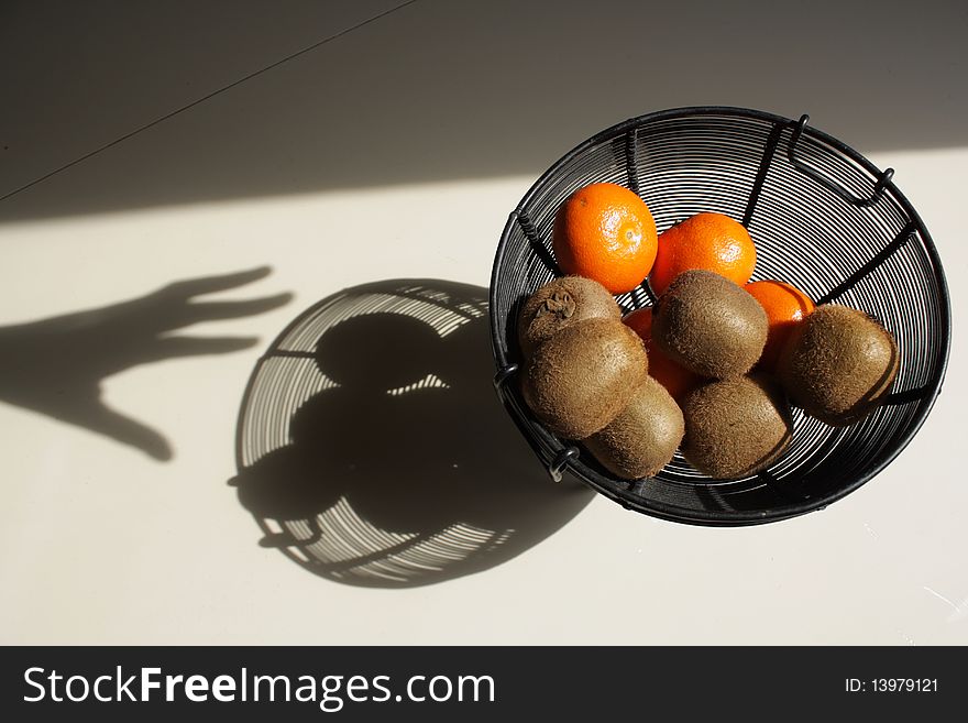 A fruit bowl with kiwis and tangerines and its shadow