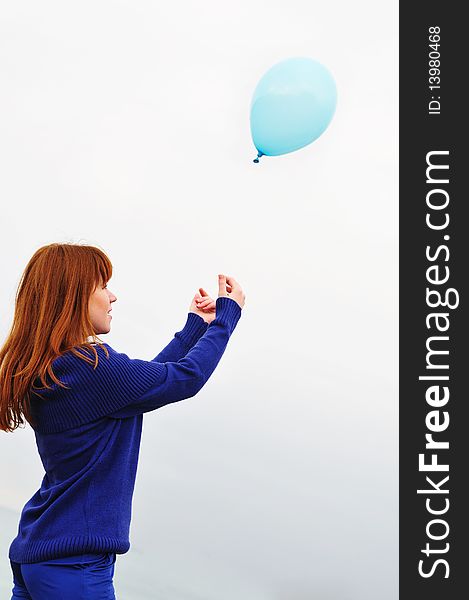 Redheaded girl playing with balloons over the spring sky