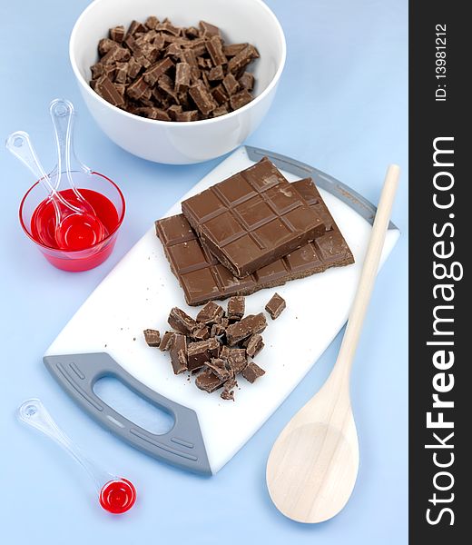 Cooking chocolate chopped on a cutting board isolated against a blue background. Cooking chocolate chopped on a cutting board isolated against a blue background