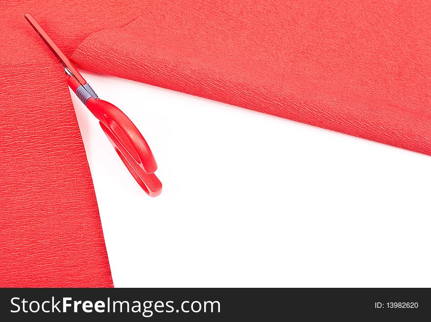 Scissors cutting red paper on white