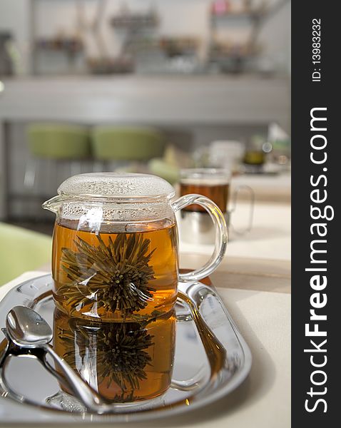 Glass tea pot with fresh green tea standing on an iron tray