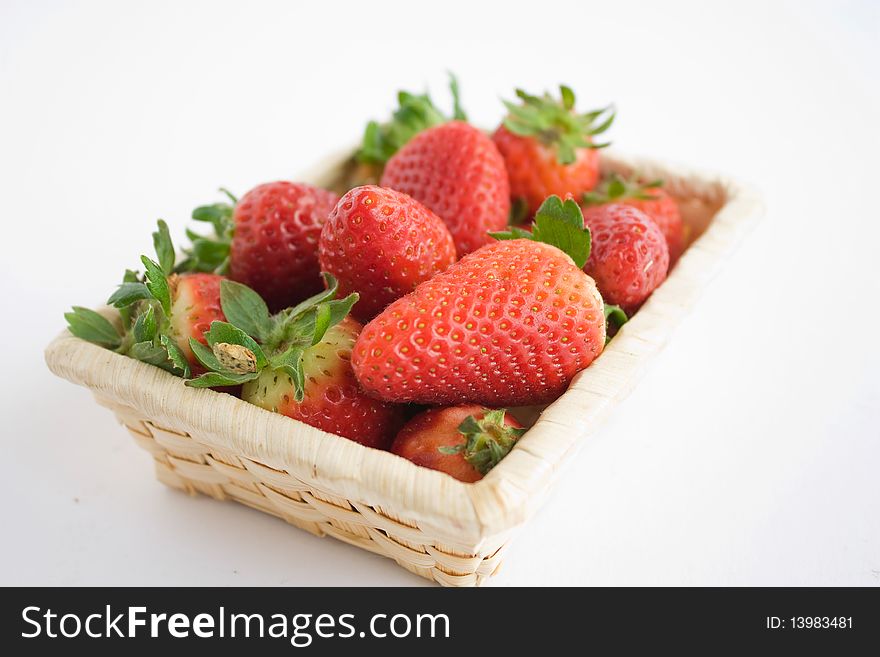 Fresh strawberries in a small basket, isolated over white