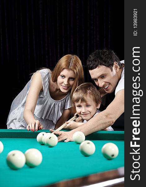 The young couple and the child plays billiards. The young couple and the child plays billiards