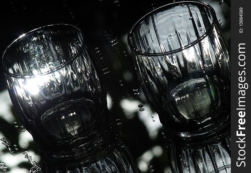 Two glasses on wet mirror reflecting sunlight. Two glasses on wet mirror reflecting sunlight