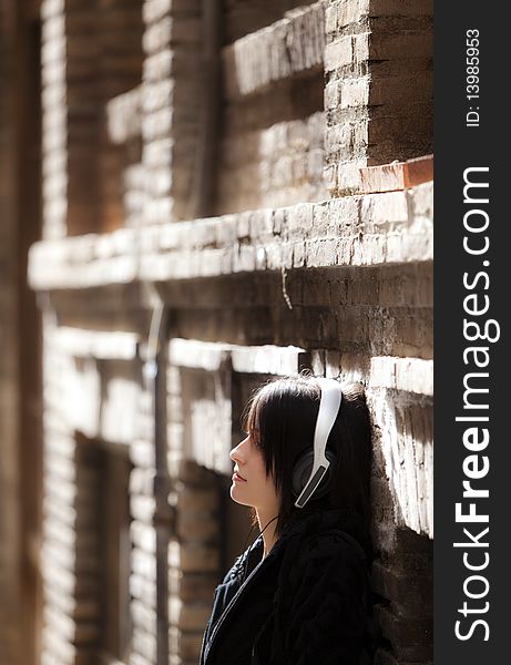 Young pierced girl listening music on urban background.