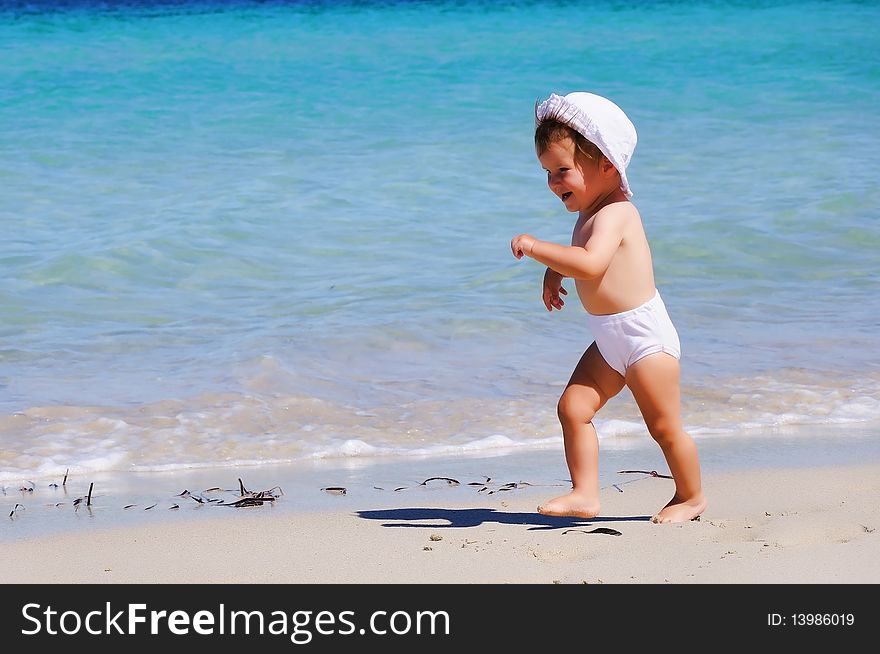 Small happy little girl running around on the beach