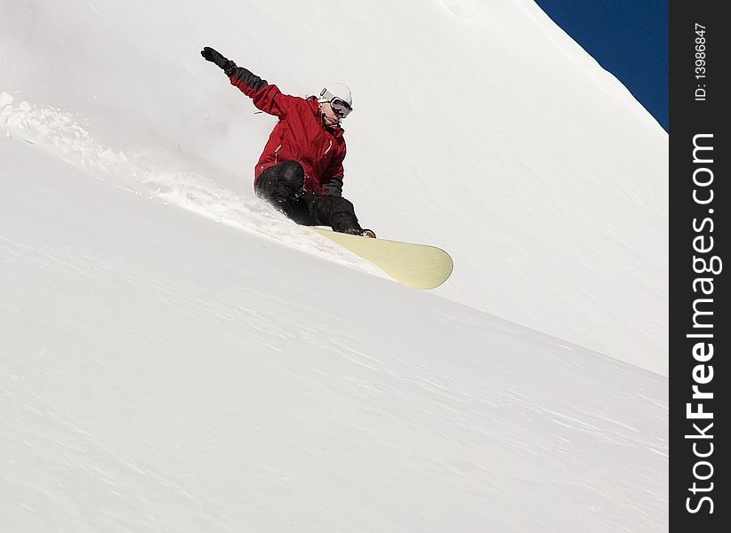 Snowboarder doing a toe side carve with deep blue sky in background