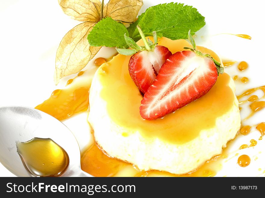 Creme caramel on a mirror of caramel splashes, decorated with strawberries, physalis and mint leaves