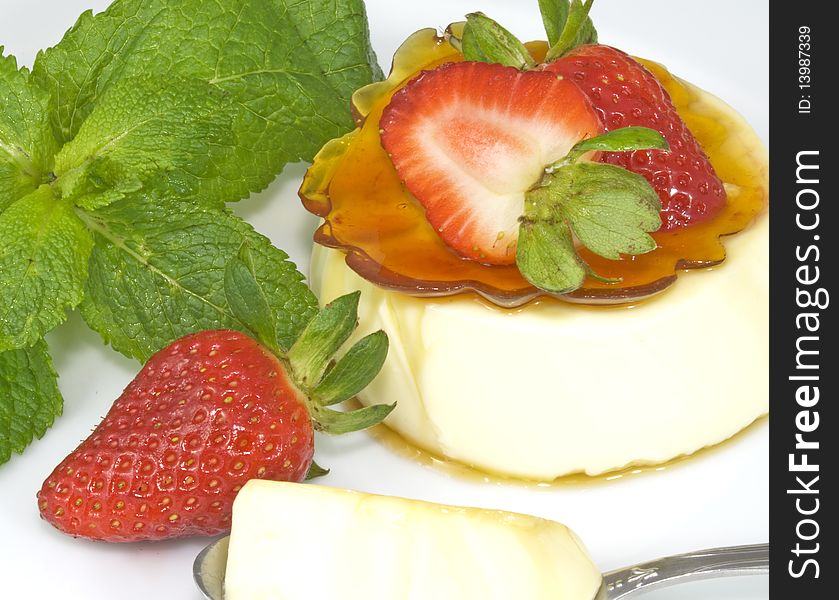 Panna Cotta with a ring of caramel and strawberries on top, decorated with strawberries and mint leaves
