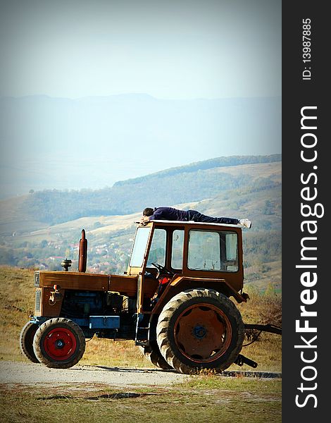 Photo of a man sleeping on his tractor during the summer season.