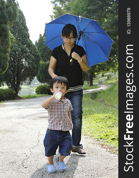 An Asian mother and her son walking in a public park. An Asian mother and her son walking in a public park