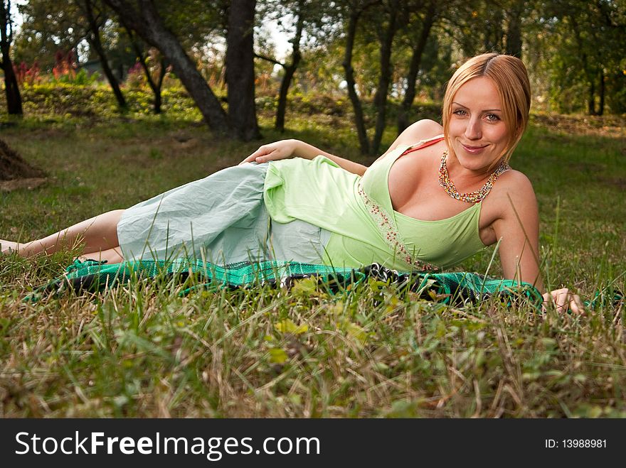 Pregnant woman on a grass and smiling