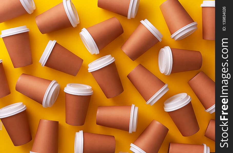 Multiple disposable coffee cups organized over yellow background