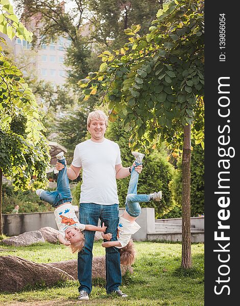 Happy father with his little son in park in sunny day. Dad holds son head down. Happy father with his little son in park in sunny day. Dad holds son head down