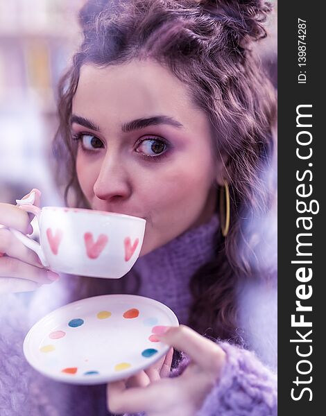 Appealing dark-haired woman with big brown eyes sipping tea