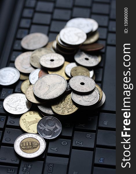 A shot of a laptop and world coins in an office environment, can be used as e-commerce concept