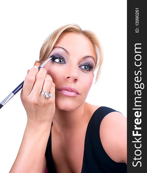 The woman  paints face with makeup, studio shot