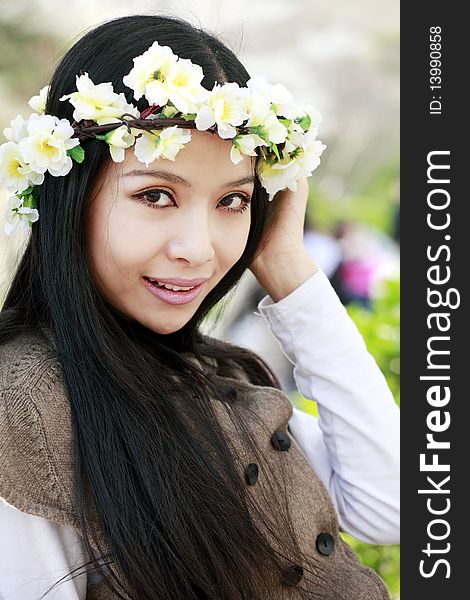 Spring portrait of young smiling girl with garlands outdoors.