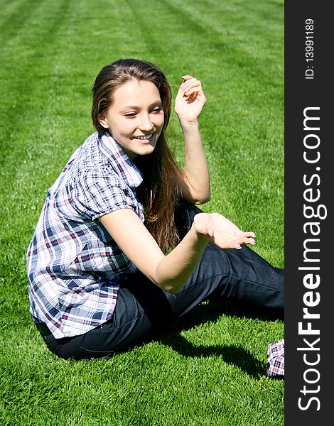 Young caucasian girl sitting on the green grass. Young caucasian girl sitting on the green grass