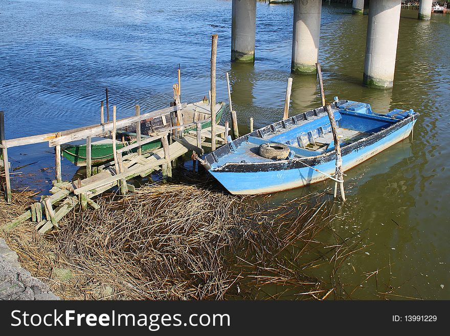 Little wooden blue boat anchored under a bridge