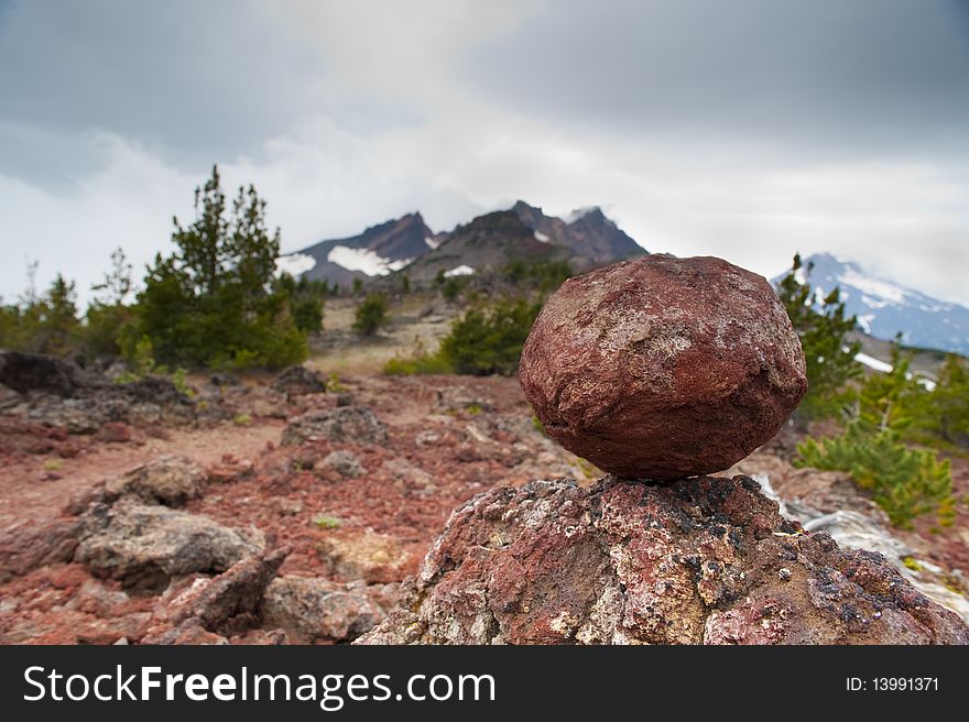 Red rock balancing on another rock, Broken Top mountain. Red rock balancing on another rock, Broken Top mountain
