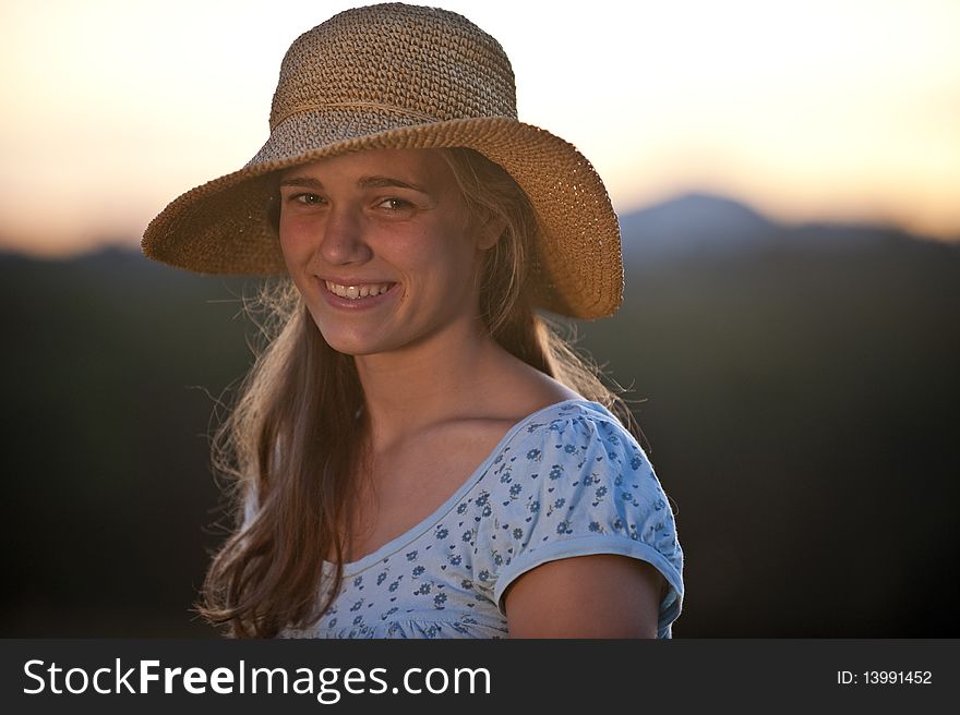 Pretty teen girl sitting in a field in the evening light. Pretty teen girl sitting in a field in the evening light