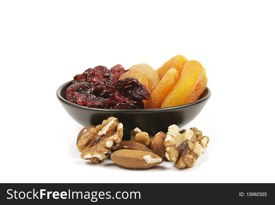 Red ripe dried cranberries and dried orange apricots with mixed nuts on a reflective white background. Red ripe dried cranberries and dried orange apricots with mixed nuts on a reflective white background