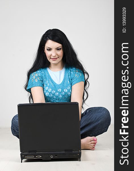 Young woman sitting with legs crossed on floor and working on laptop,see more in People on couch or wooden floor. Young woman sitting with legs crossed on floor and working on laptop,see more in People on couch or wooden floor