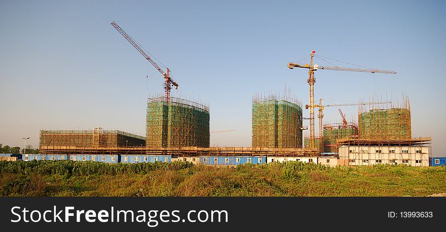 The tower crane on a building site, an incomplete building in the field