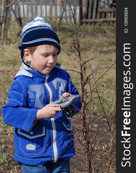 The little boy cuts off branches on an apple-tree in the spring. The little boy cuts off branches on an apple-tree in the spring