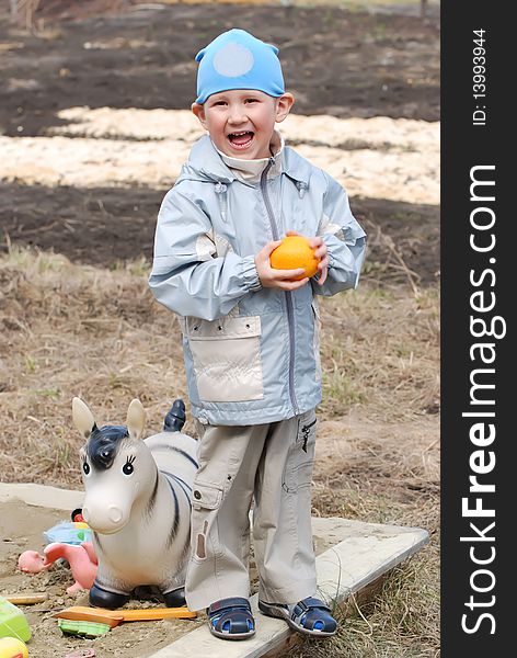 The boy plays in the street with toys and has control over an orange. The boy plays in the street with toys and has control over an orange