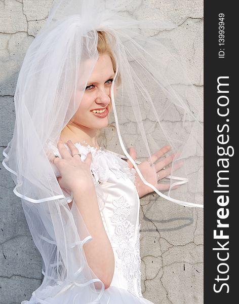 Portrait of the bride in a white dress with a diadem in hair and red rose in studio