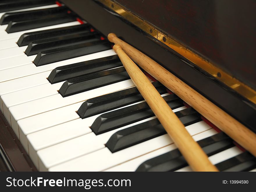 Drum sticks on black and white piano keyboard. For concepts like music and creativity. Drum sticks on black and white piano keyboard. For concepts like music and creativity.