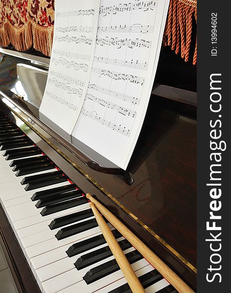 Music Score And Drum Sticks On Piano Keyboard