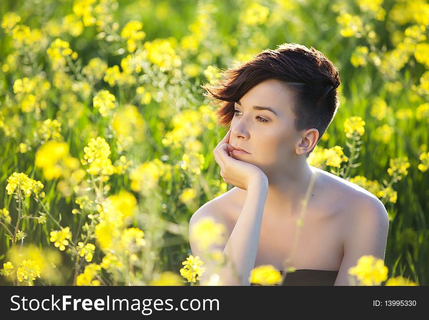 Young beautiful pensive girl on a green field full of flowers. Young beautiful pensive girl on a green field full of flowers.