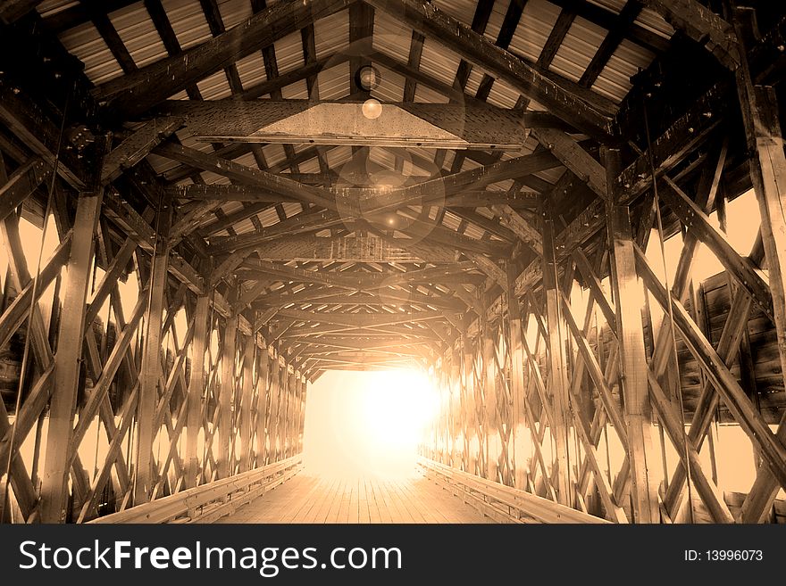 View of the interior wood structure of a covered bridge in sepia with lens flare. View of the interior wood structure of a covered bridge in sepia with lens flare